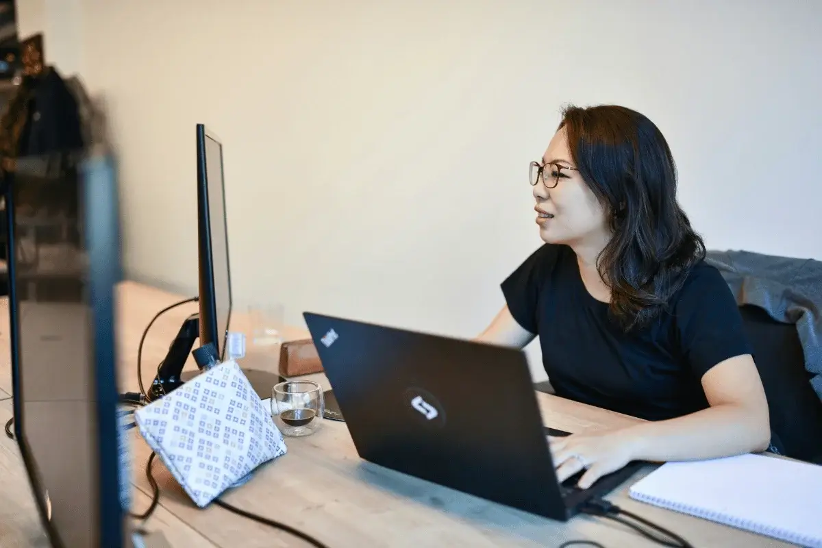 Woman working at dual monitors in modern office.
