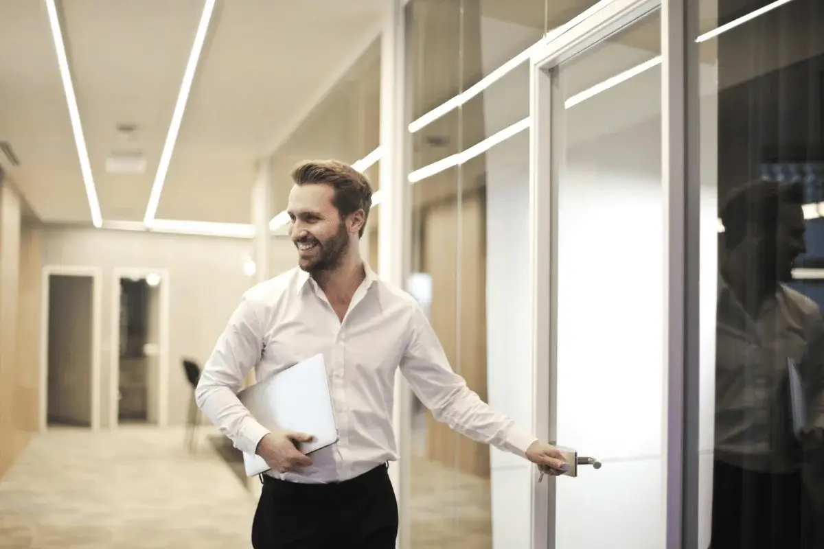 Professional man entering modern office with glass walls.
