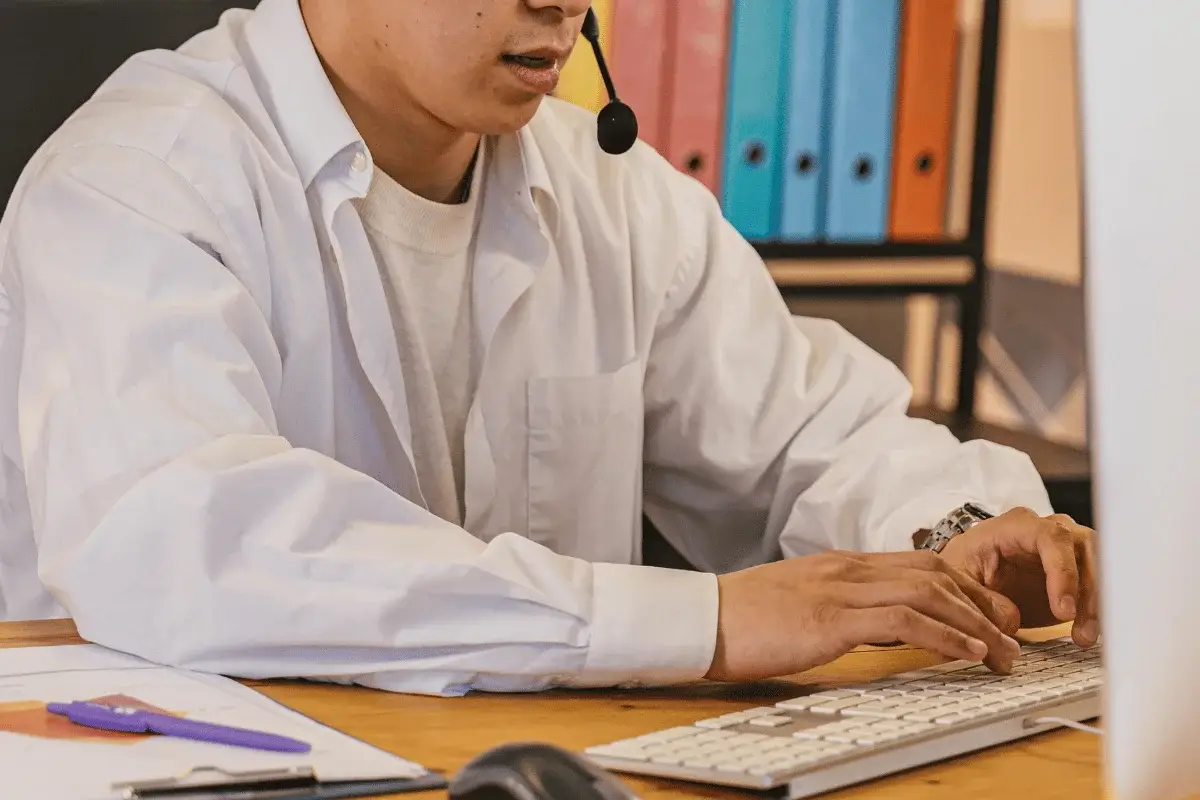 Customer service representative typing at desk with headset on.