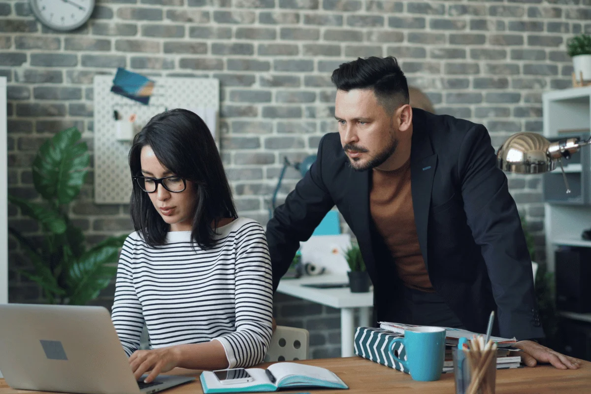 Marketing professionals discussing business growth metrics with printed reports and a laptop on the desk.