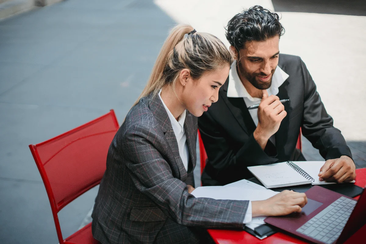 Business professionals working together on a laptop outdoors.