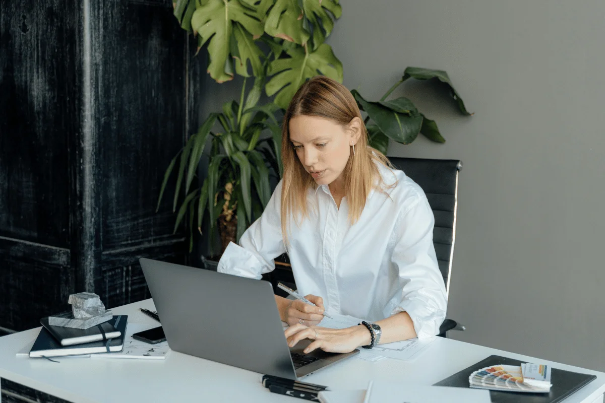 Woman working on a laptop at a modern office desk.