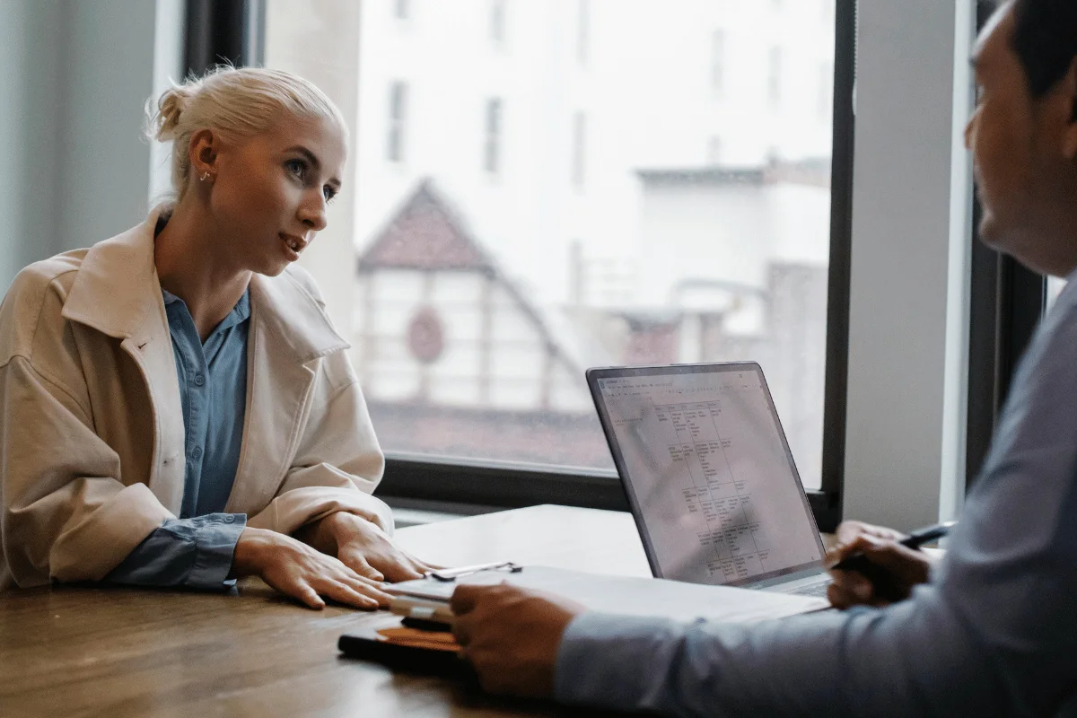 Businesswoman discussing work with colleague at desk.