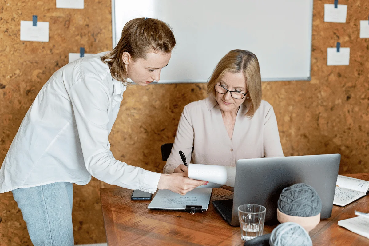 Business partners working together at a wooden desk with a laptop.