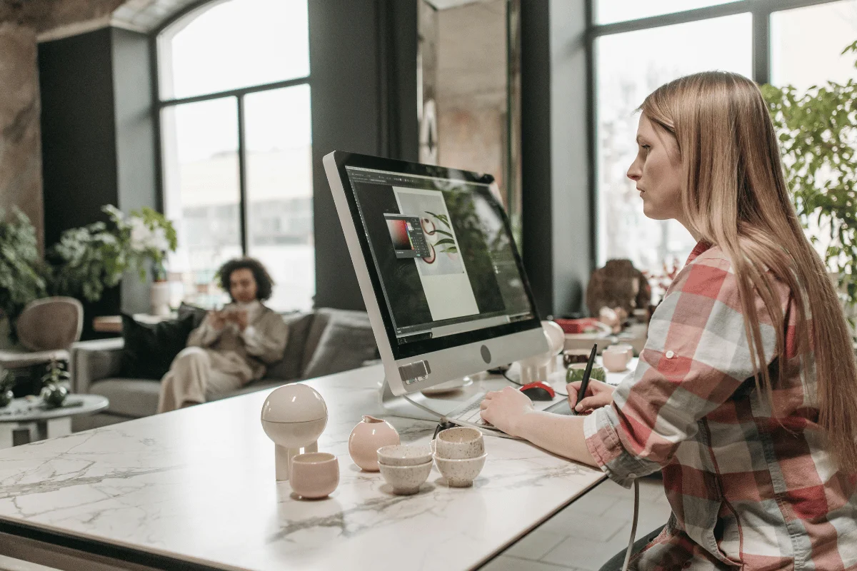 A female graphic designer working on a digital design project on a computer.