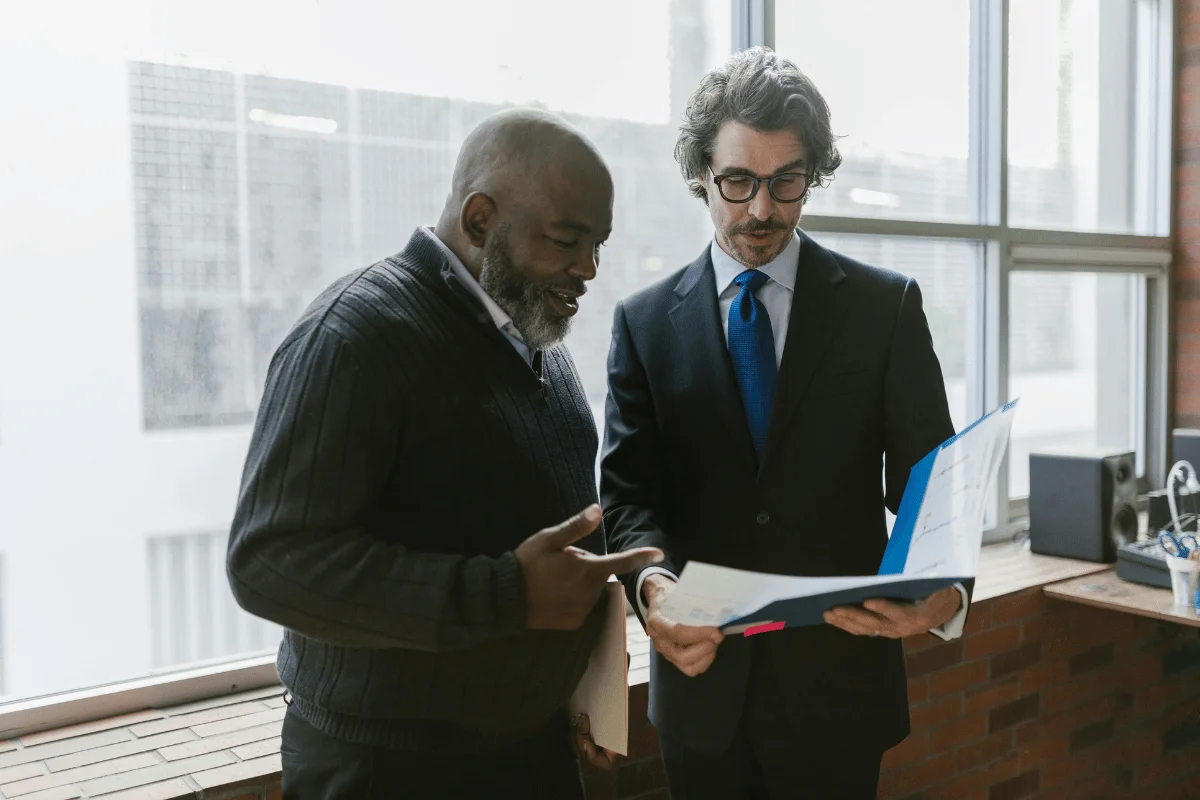 Two businessmen discussing financial documents in a modern office.