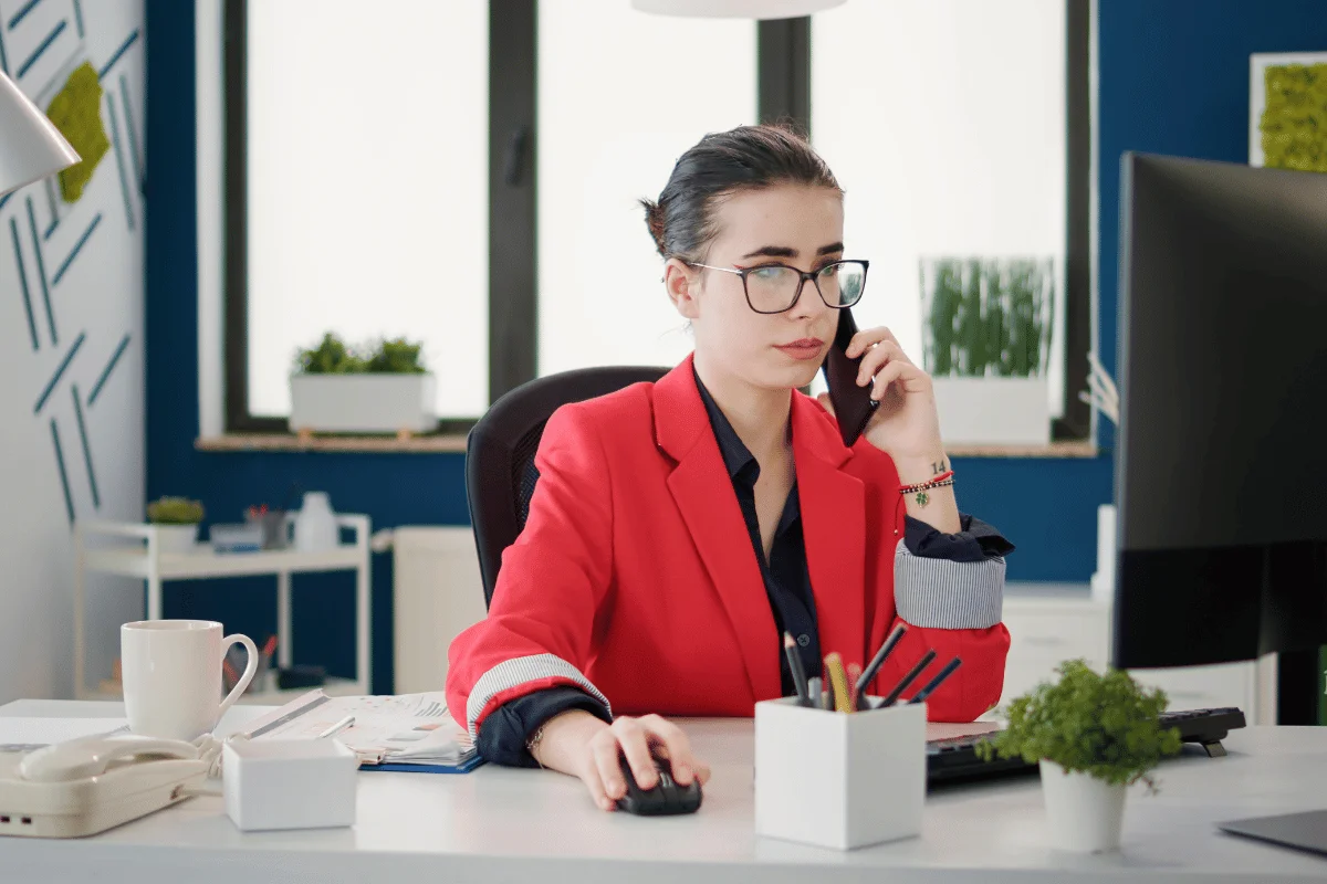 Professional woman using a phone and computer in an office.