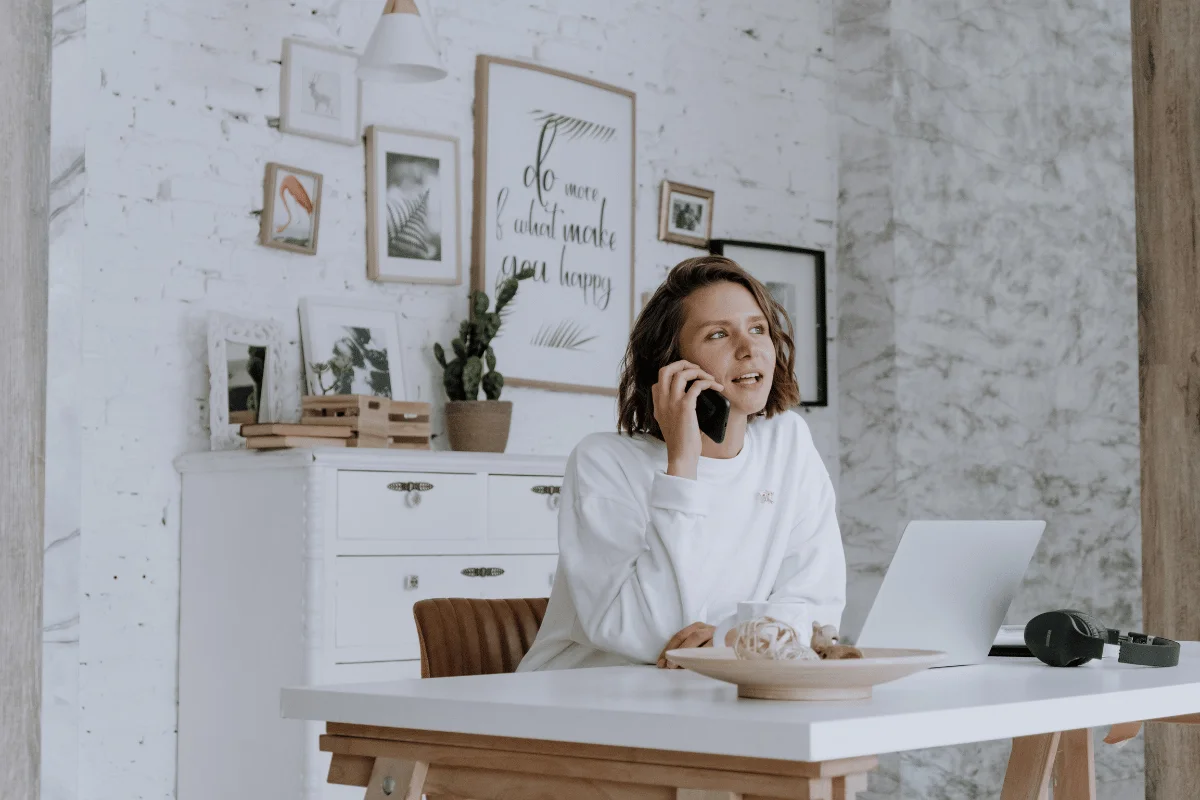 A woman talking on the phone while working at her desk in a modern office.
