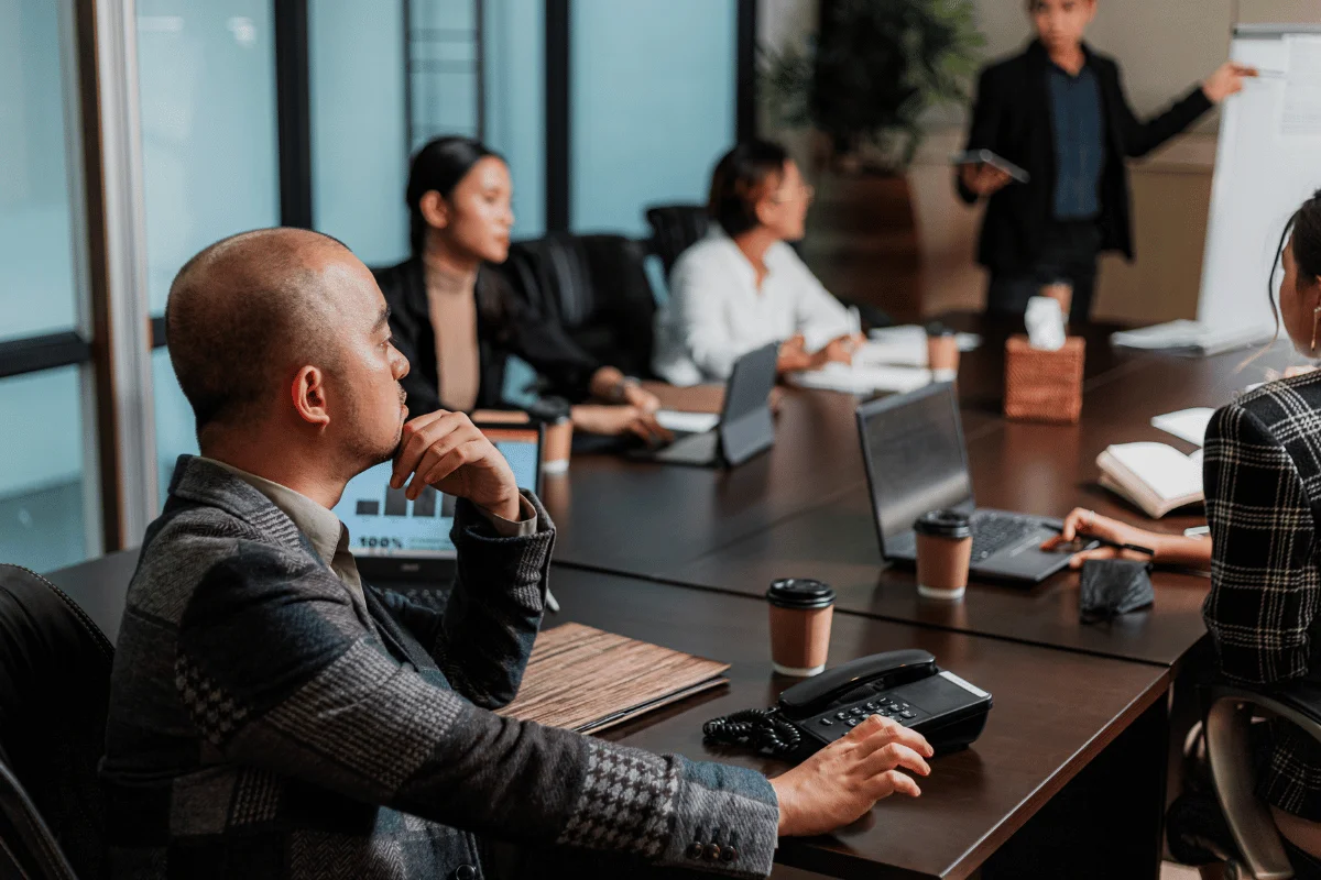 Group of professionals in a meeting, with one person presenting and others listening.