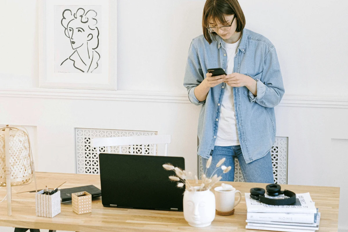 A woman standing and checking her phone in a modern home office.