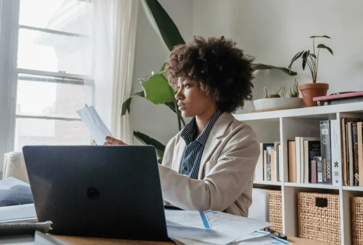 Businesswoman working remotely with papers and laptop.