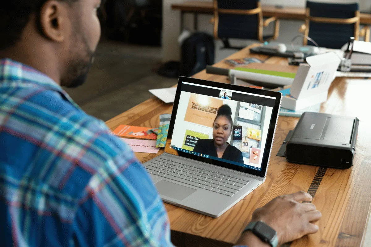 Man in video call with woman discussing business on laptop.