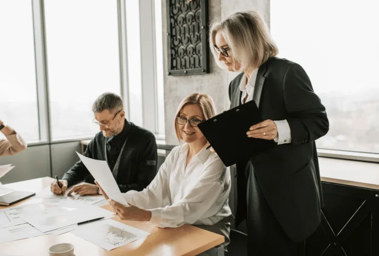 A business meeting at a conference table with charts, graphs, and engaged professionals discussing documents and strategies.