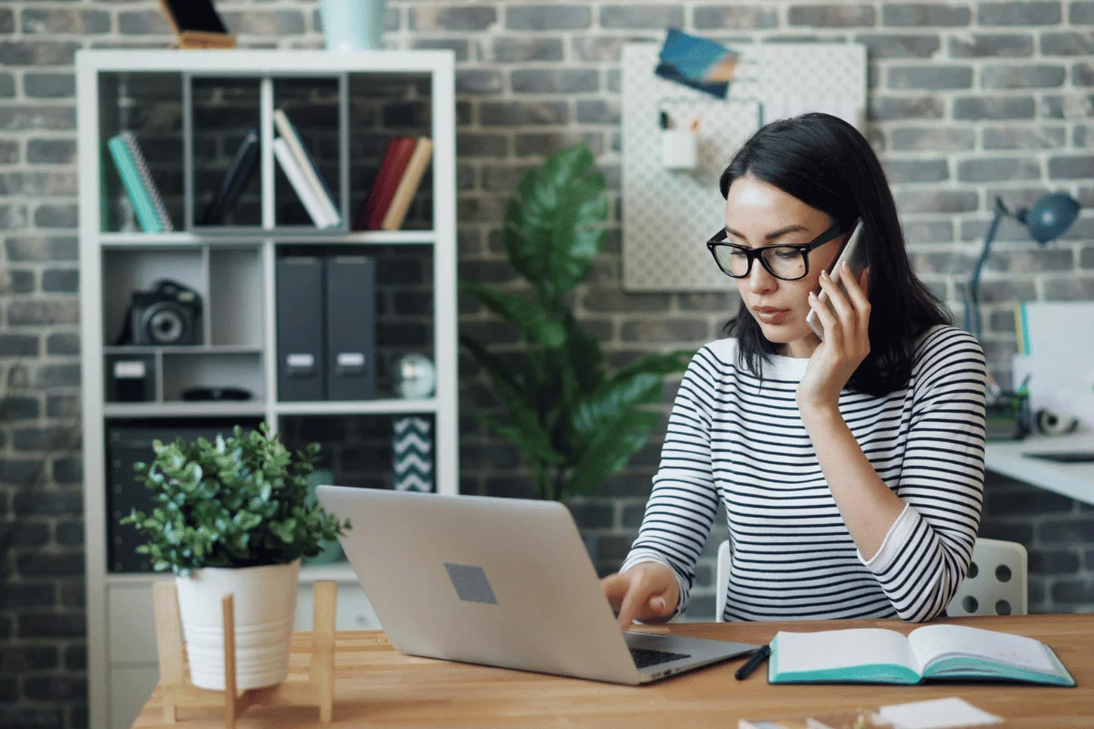 Focused professional multitasking with phone and computer.