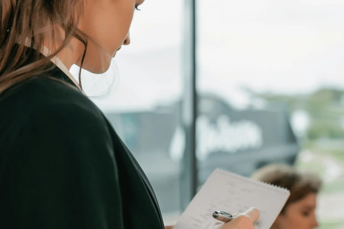 Woman holding notepad and pen during a professional meeting.