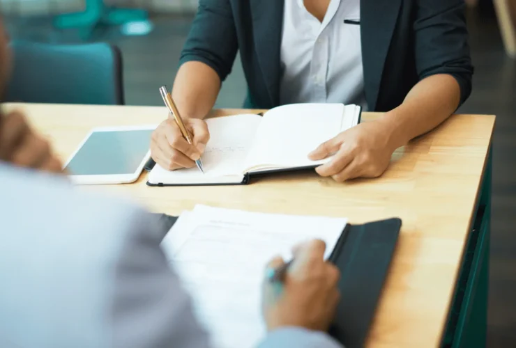 Two professionals reviewing paperwork during a discussion.