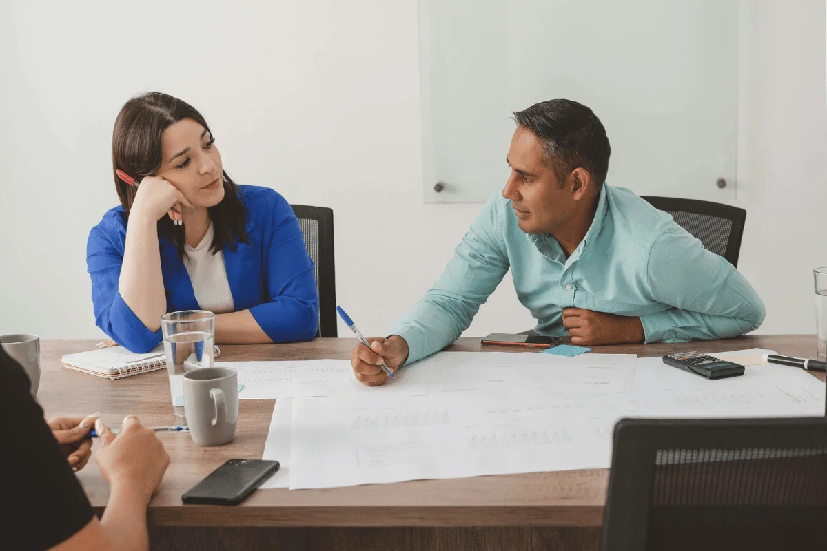 A professional meeting at a conference table with charts and notes, featuring people engaged in discussion and brainstorming.