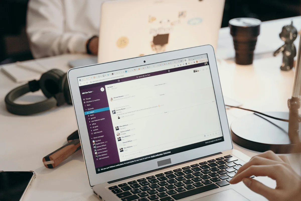 A professional using a laptop to communicate on Slack in a collaborative work environment.