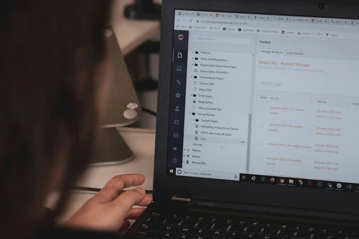 A person using a laptop with a content management system open, displaying a list of pages and redirects. The scene conveys focus and concentration.