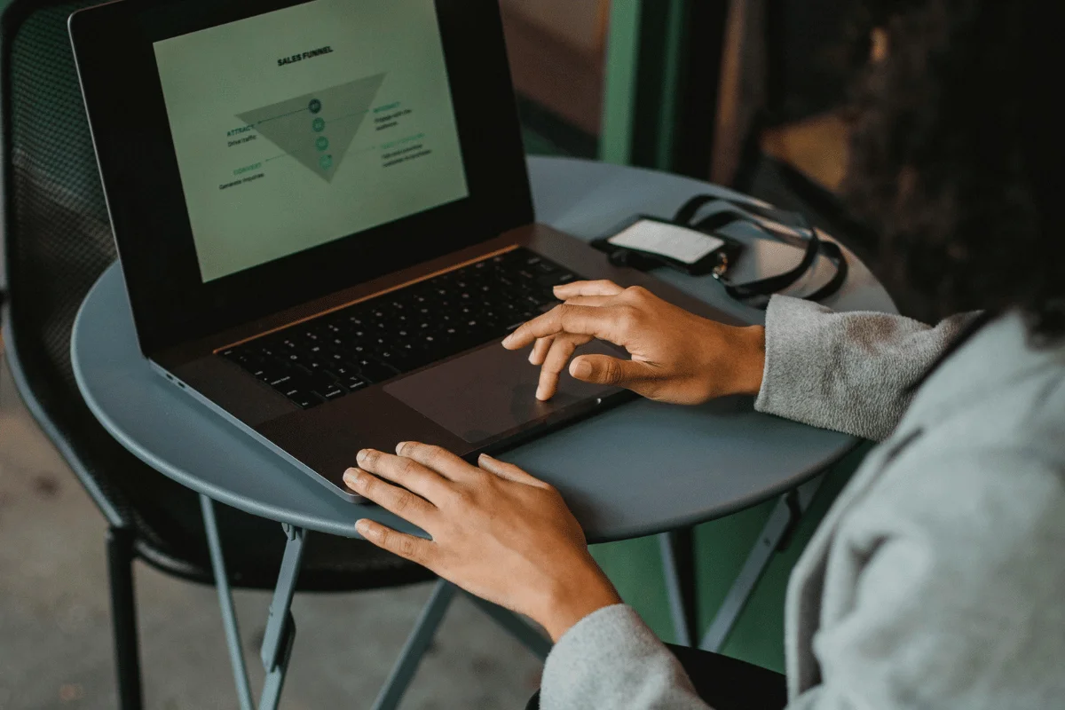 Woman analyzing a sales funnel graphic on laptop screen.