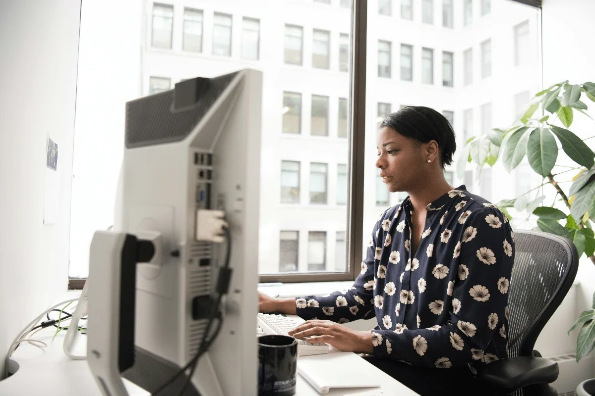 Woman working at office desk using desktop computer.