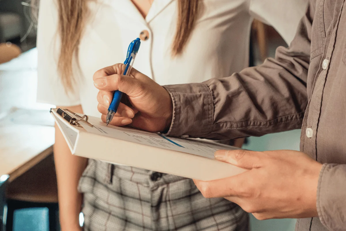 Businessman writing notes on clipboard during meeting.