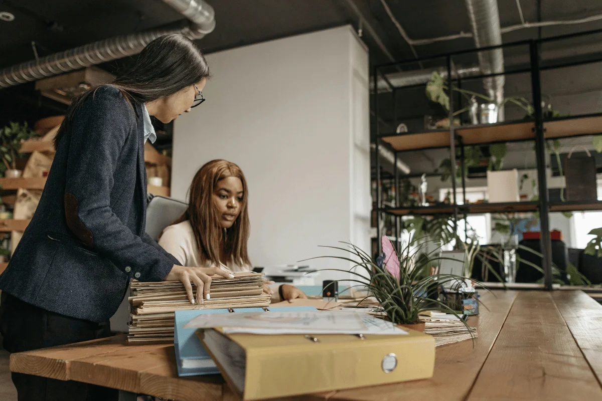 Two professional women managing paperwork and administrative tasks.
