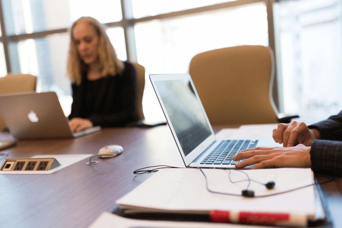 Professionals focused on laptops in modern conference room.