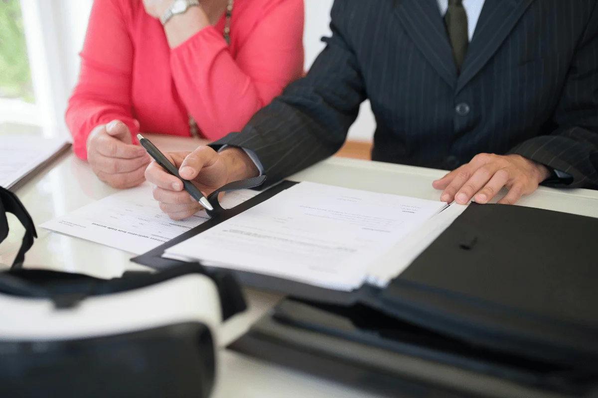 Two people sit at a table reviewing documents. 