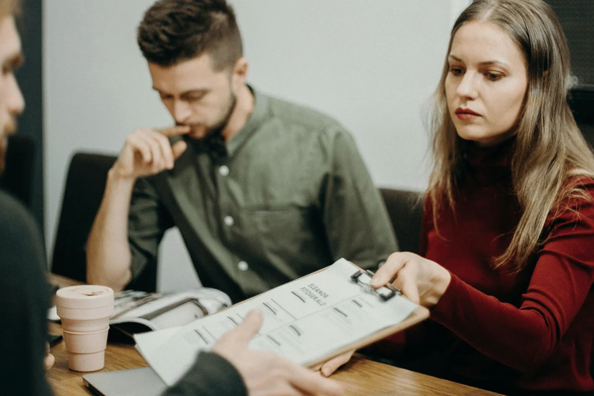 Business meeting where woman hands a clipboard to a colleague.