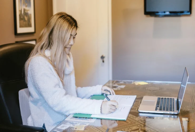 Woman focused on writing in a planner at her desk.