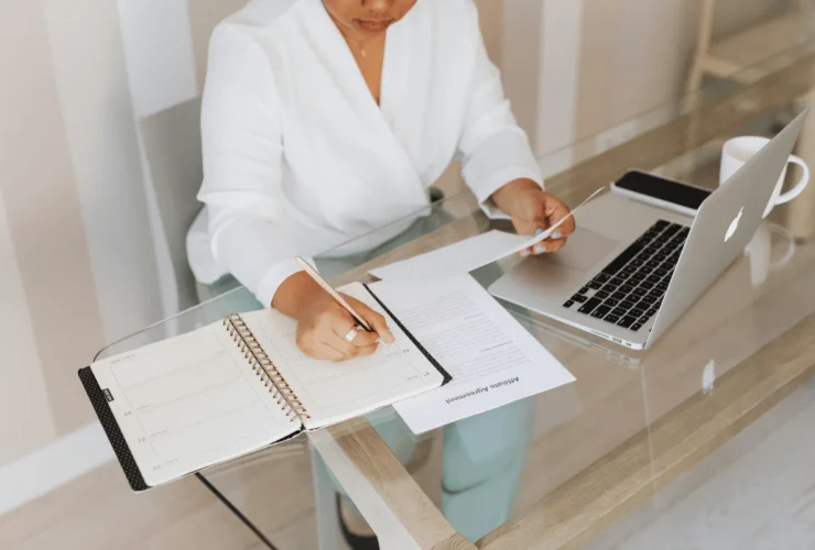 A woman in formal attire managing paperwork and planning her schedule in a bright office space.