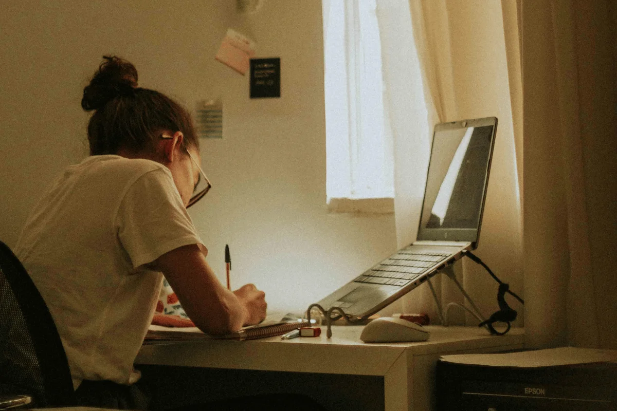 Focused student writing notes while attending an online class.