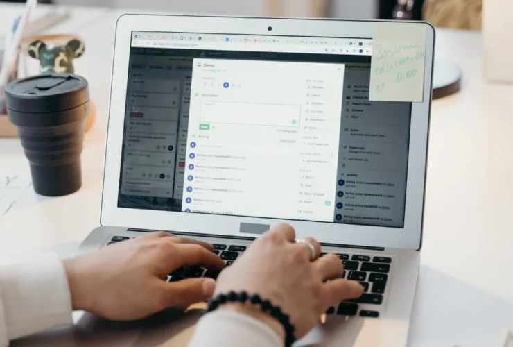 Person typing on laptop displaying email inbox management interface with multiple message folders open on screen.
