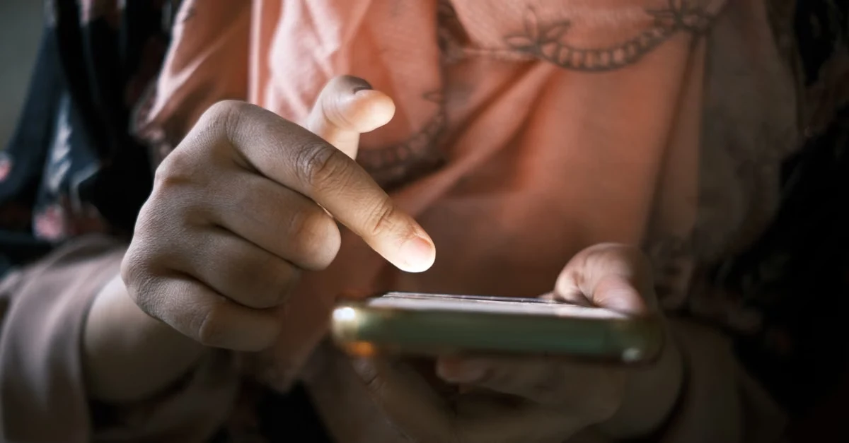 Person checking mobile phone for email inbox management notifications in low light.