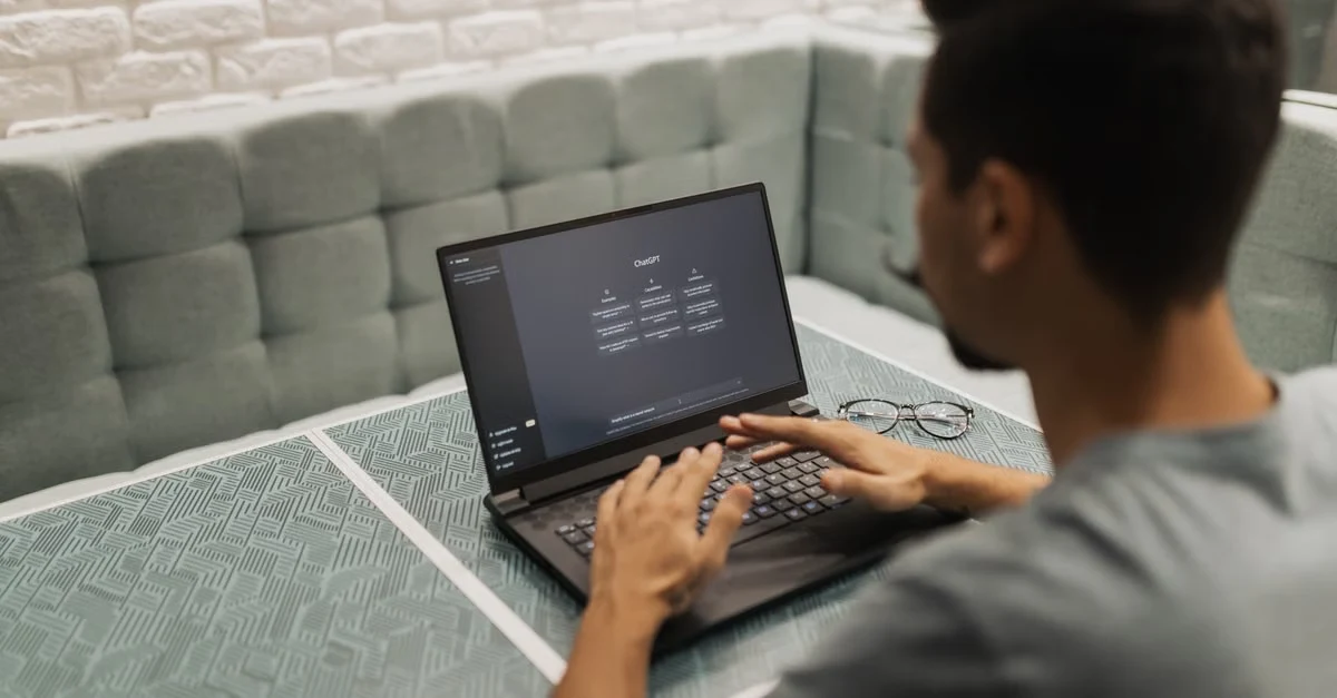 Executive assistant using laptop with AI interface, developing modern executive assistant skills in collaborative workspace.