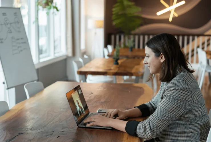 Woman on video call in modern workspace with laptop.