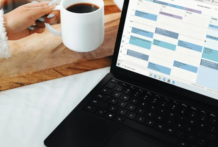 Person reviewing a digital monthly calendar on a laptop with event icons and scheduling controls.
