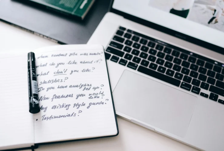 Notebook with handwritten notes and pen beside laptop for AI for executive assistants planning.