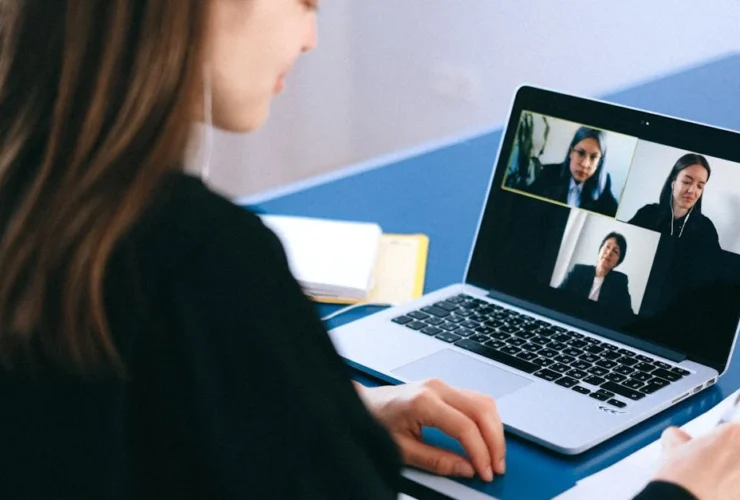 Woman participating in video call with multiple colleagues on laptop screen for calendar management virtual assistant.