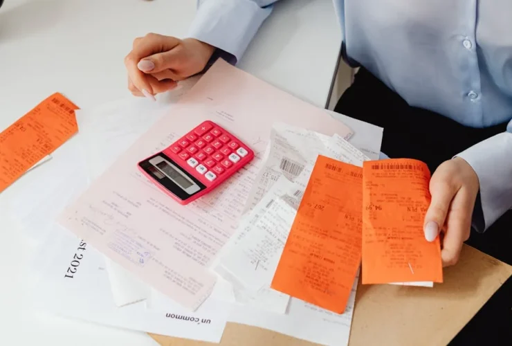 Professional reviewing budget documents with calculator and orange folders on desk for EA finance collaboration.