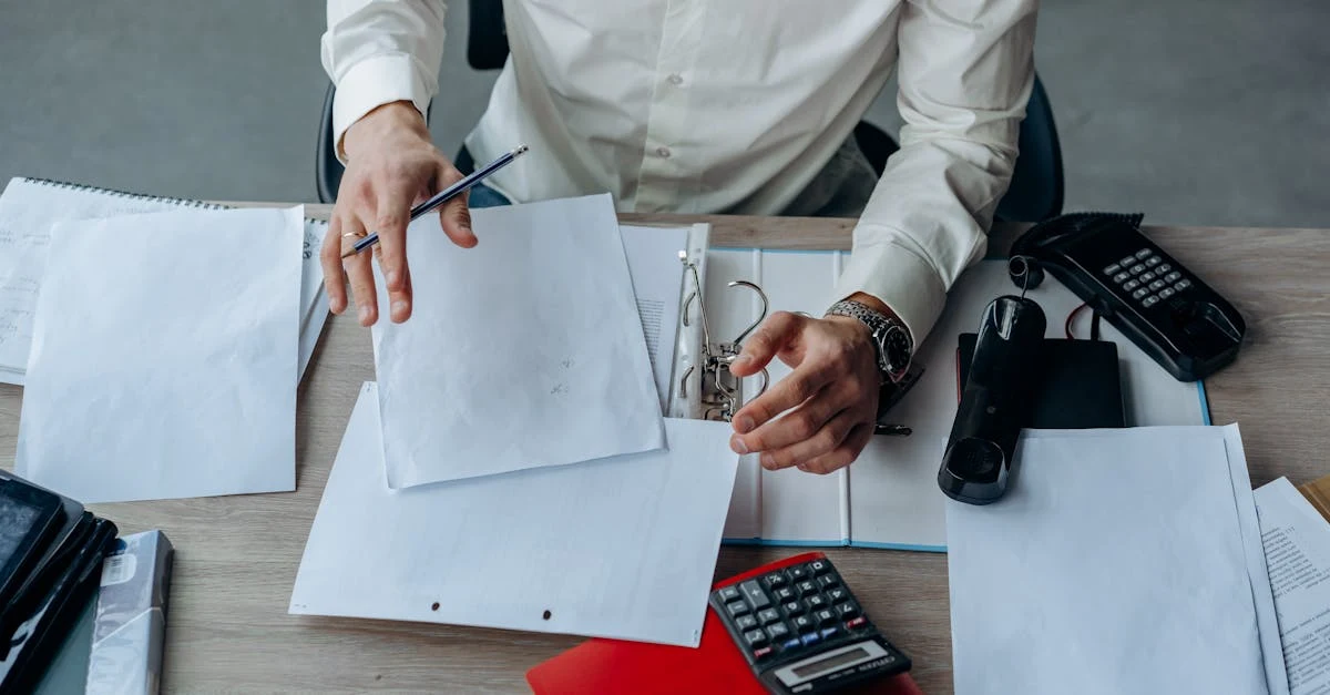 Accountant organizing financial documents and reports at desk with calculator for EA finance collaboration workflow.