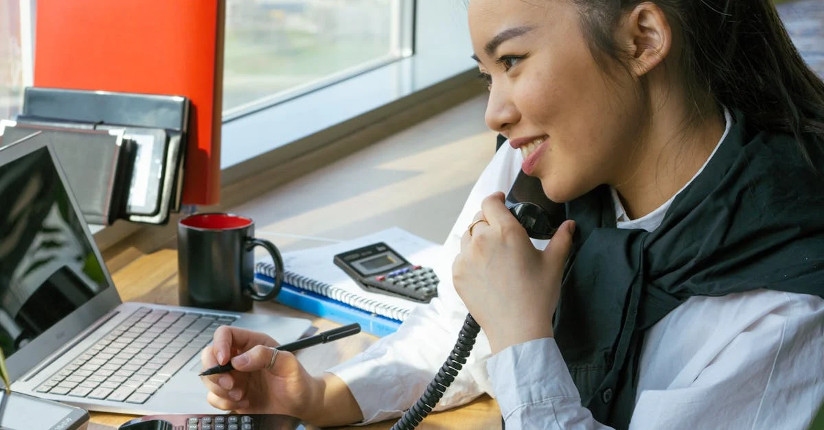 Woman using AI for executive assistants tools while on phone call at modern office desk with laptop.