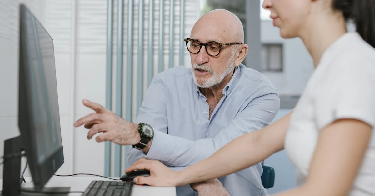 Senior manager discussing AI for executive assistants workflow with colleague at computer in modern office.