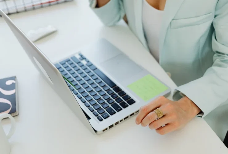 Professional managing crisis PR coordination tasks at laptop with organized workspace and communication tools visible.