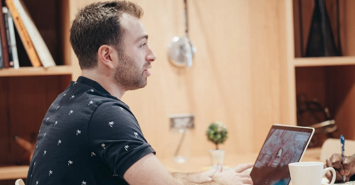 Man in black patterned shirt sitting at desk with laptop during virtual EA investor meetings.