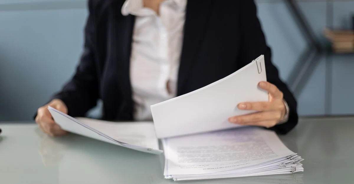 Professional woman reviewing documents at desk during investor meeting preparation and discussion.