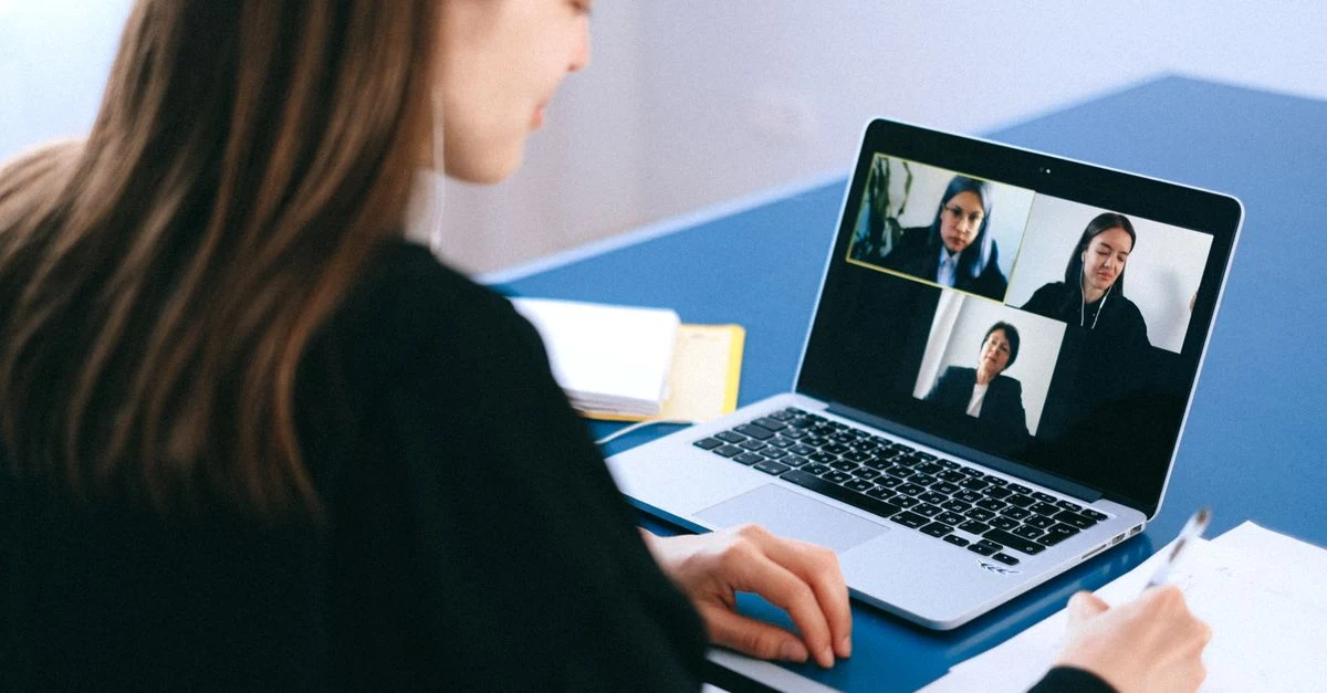 Woman conducting remote video conference on laptop with multiple team members during virtual assistant nonprofit meeting.