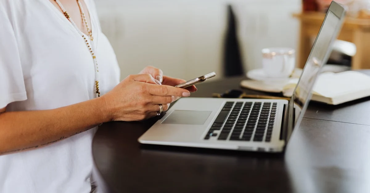 Woman at desk holding stylus with laptop, demonstrating virtual assistant skills for remote work.