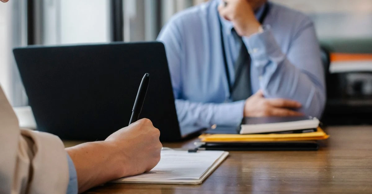 Two professionals discussing virtual assistant nonprofits at table during business interview meeting.